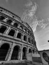 Black and white low angle of Colosseum with arched windows and fence for restoration in Rome