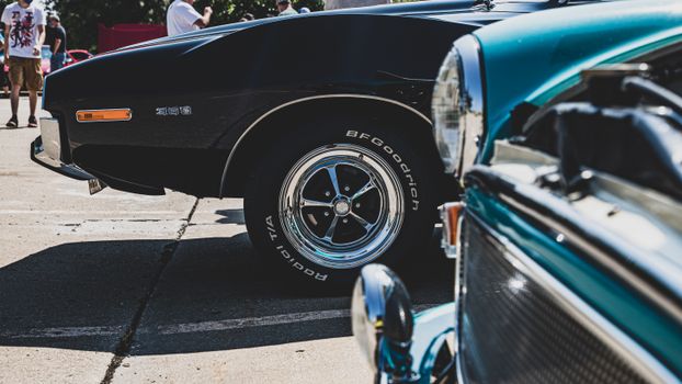 Close-up of classic cars at a public show in Kansas City, highlighting vintage chrome details and wheels.