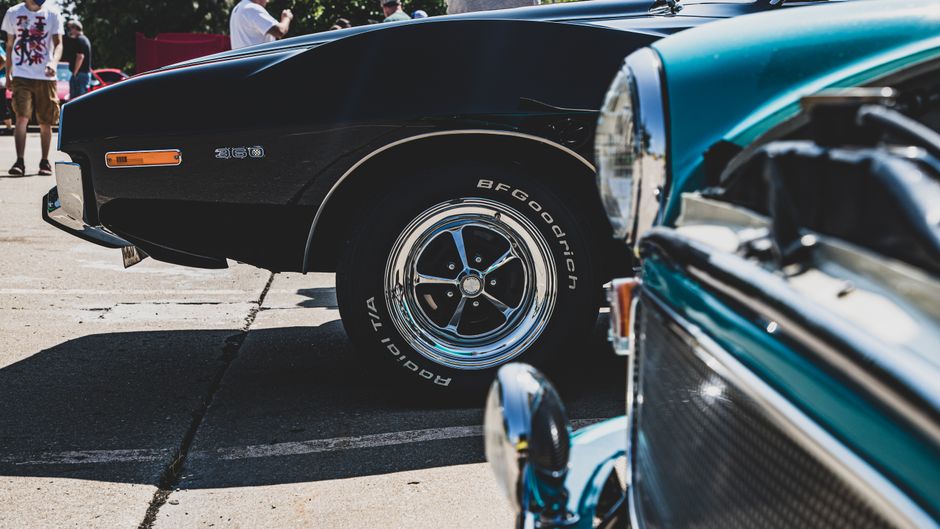 Close-up of classic cars at a public show in Kansas City, highlighting vintage chrome details and wheels.