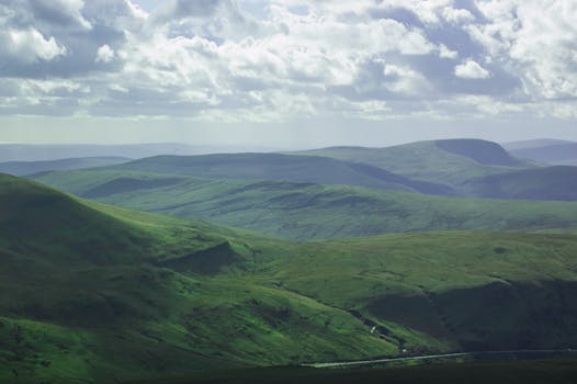 Expansive green hills and valleys under a dramatic cloud-filled sky.