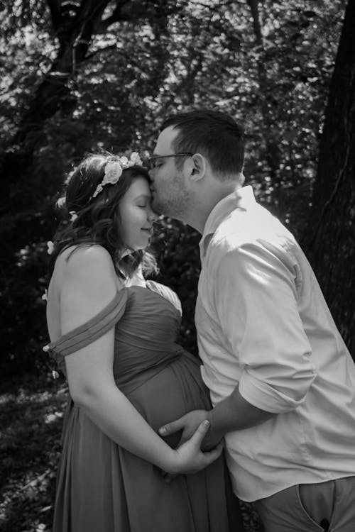Grayscale Photo of a Man Kissing a Pregnant Woman 