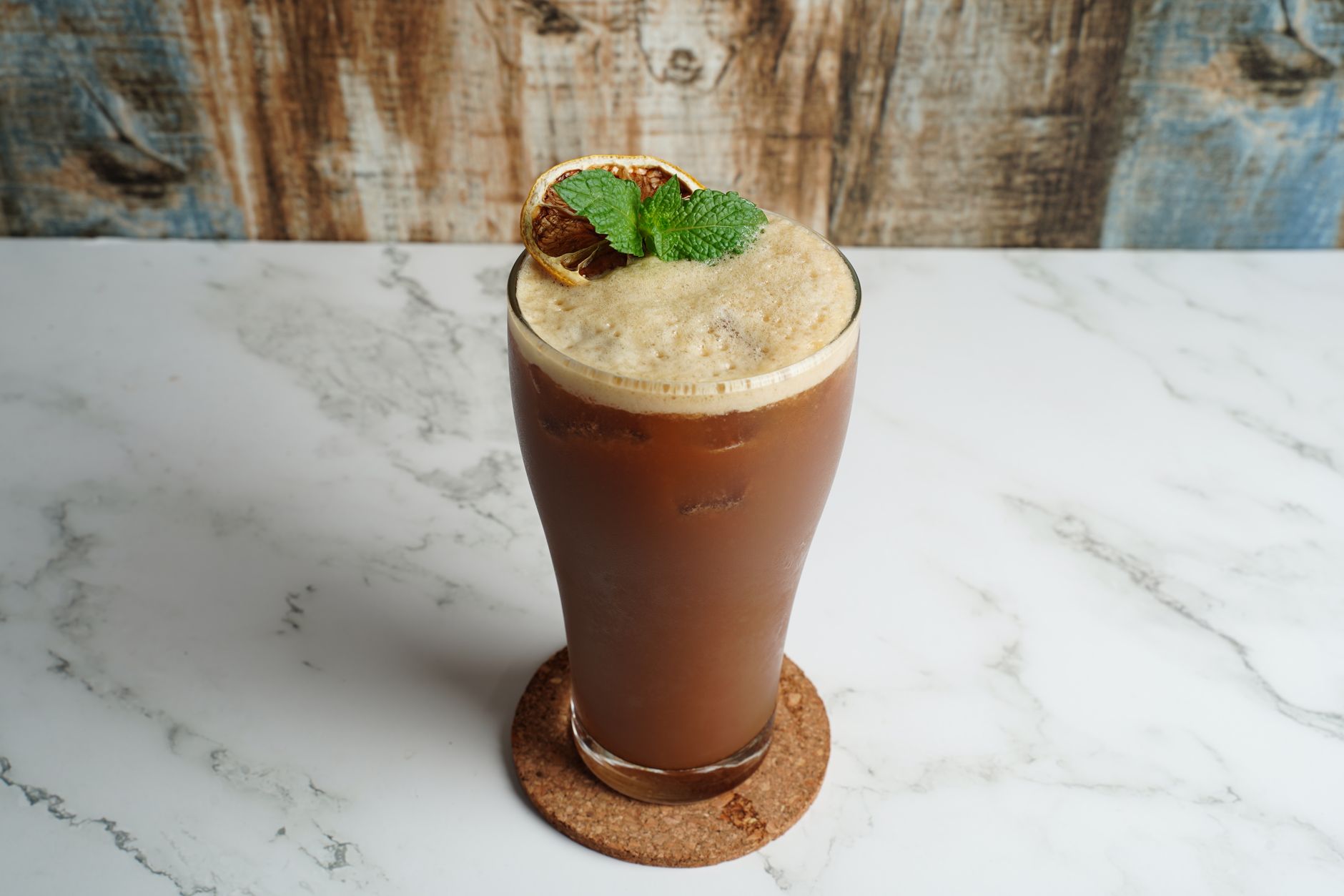 Delicious iced coffee topped with fresh mint and lime, perfect for a refreshing break.