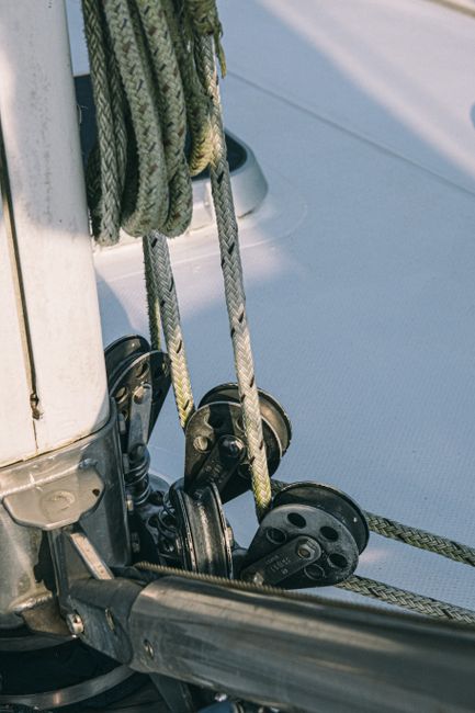Metal mechanism of sailing boat with rope placed on edge of white bow in sunlight in daytime in summer outside