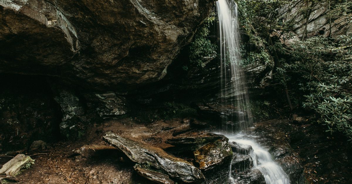 Serene waterfall flowing over mossy rocks in Danbury, NC surrounded by lush greenery.
