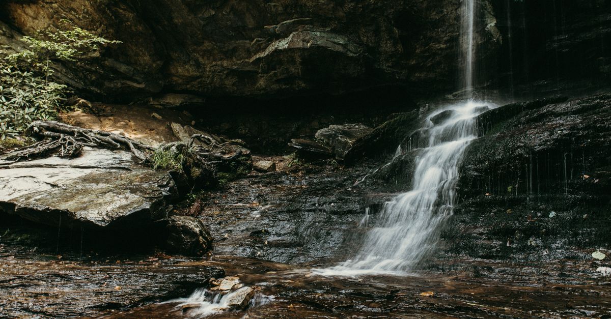 A serene waterfall cascades gently over rocky terrain in a lush North Carolina forest.
