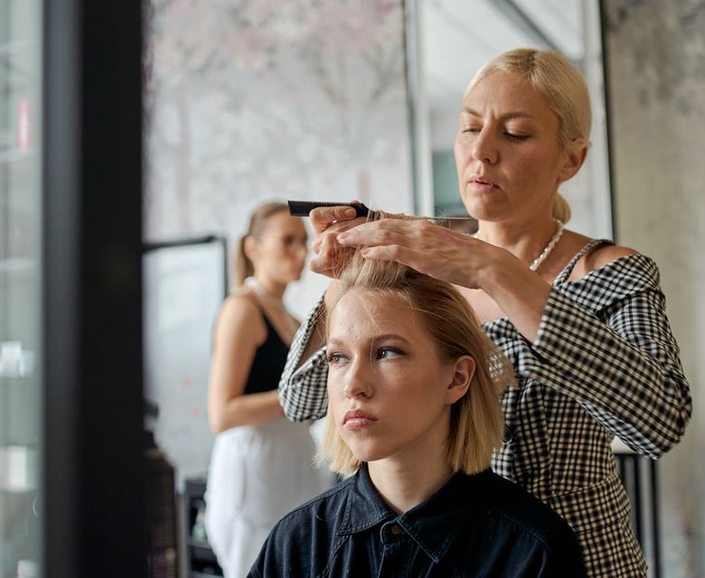 Female hairstylist smoothing a client's hair with an iron