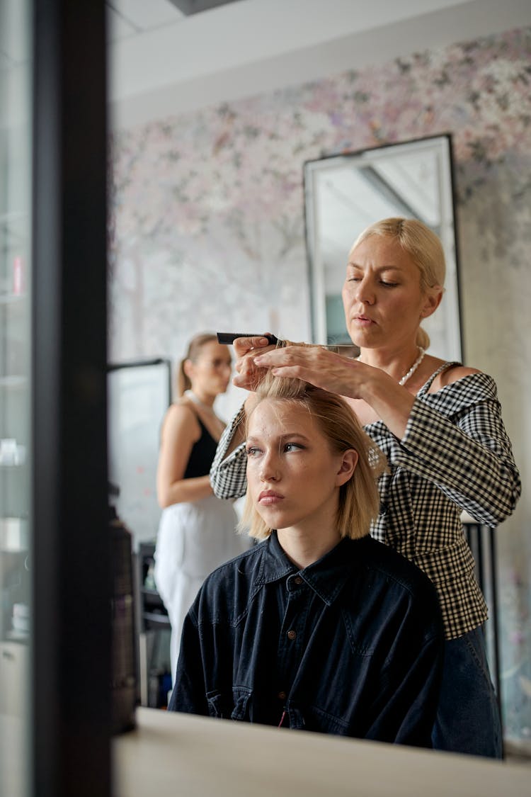 Concentrated Hairdresser Straightening Hair Of Woman In Salon