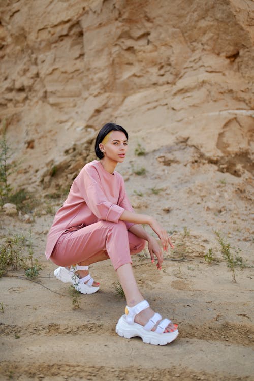 Stylish woman in modern sandals squatting in mountains