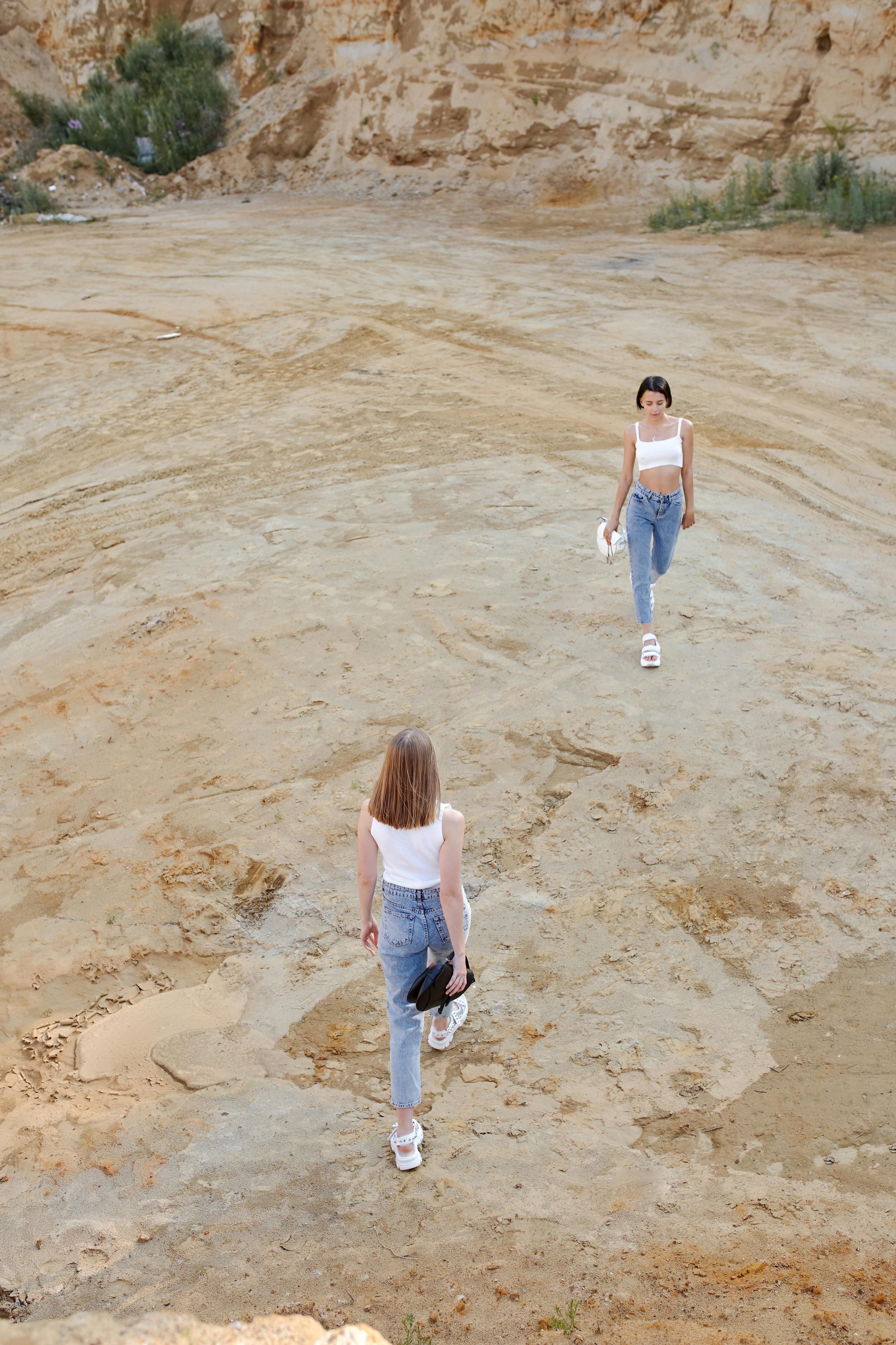 unrecognizable models walking in desert near mountain