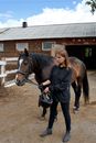 Woman with horse in paddock near stable