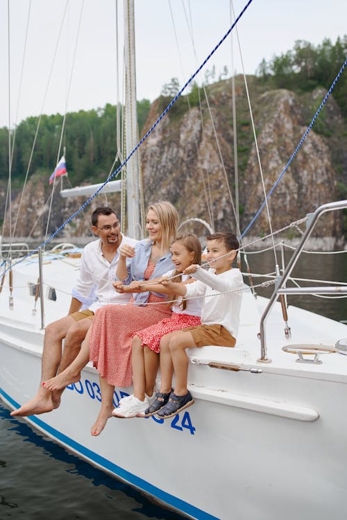 Free Full body of happy parents and children spending time together on sailboat in sea Stock Photo