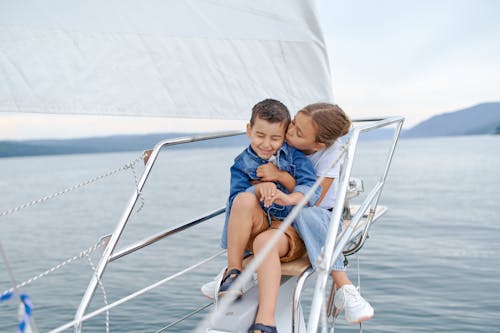 Little girl kissing brother on sailboat