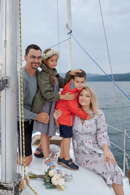Smiling family in casual clothes resting together on yacht in sea and looking at camera