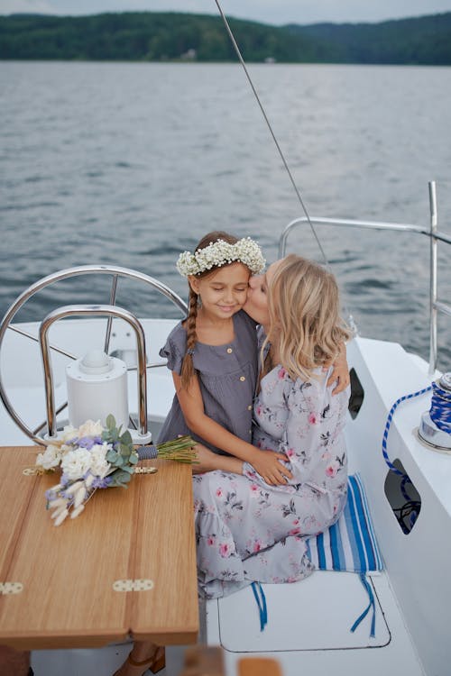 Mother kissing daughter on motor boat during trip