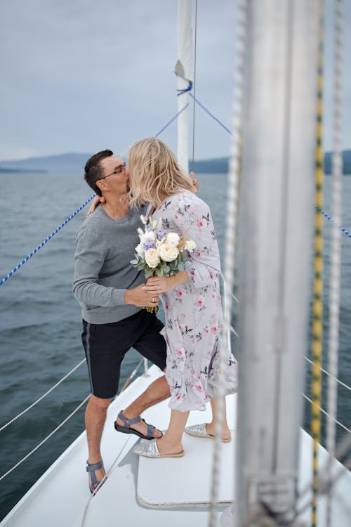 不可識別的女人在旅途中親吻遊艇上的男朋友