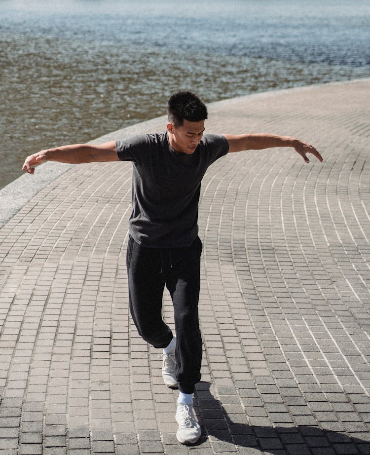 Asian Break Dancer With Raised Arms On Embankment