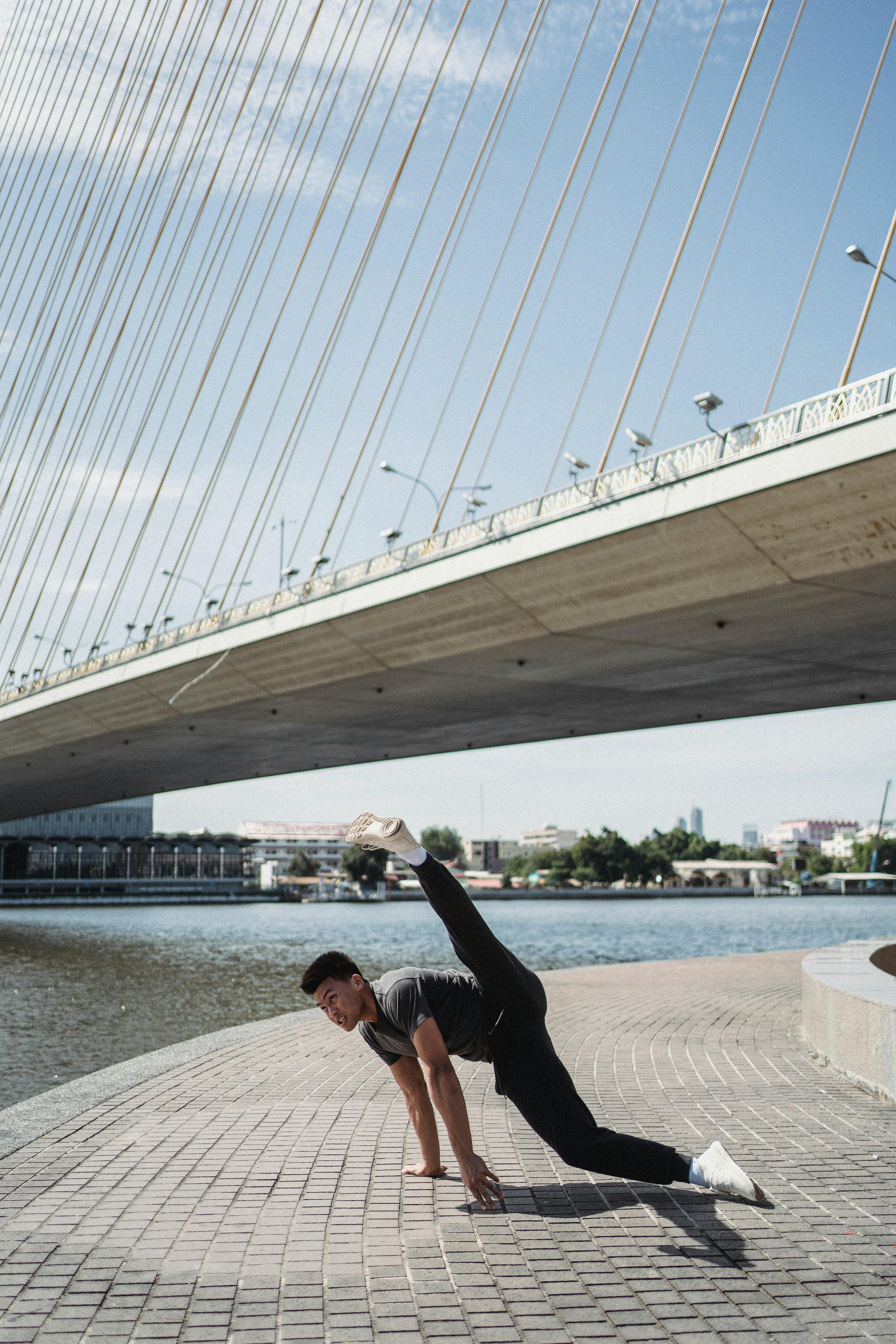 年轻的男舞者在河边的钢桥下活力四射地表演着