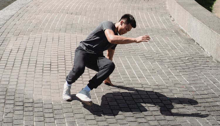 Energetic Asian Man Dancing Street Dance On Sidewalk