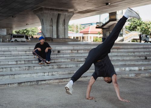 Free Full body determined male dancer wearing sports clothes performing street style dance on handstand while practicing under urban elevated road Stock Photo