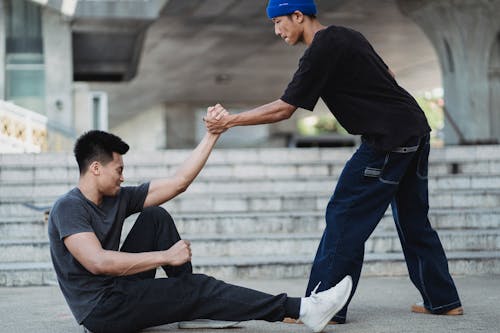 Homme Asiatique Aidant Un Ami à Se Lever Du Sol