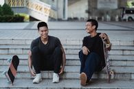 两个年轻人在城市楼梯上笑着玩滑板，享受休闲时刻