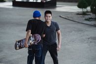 Cheerful young Asian men in casual clothes bumping shoulders and smiling while greeting each other on street
