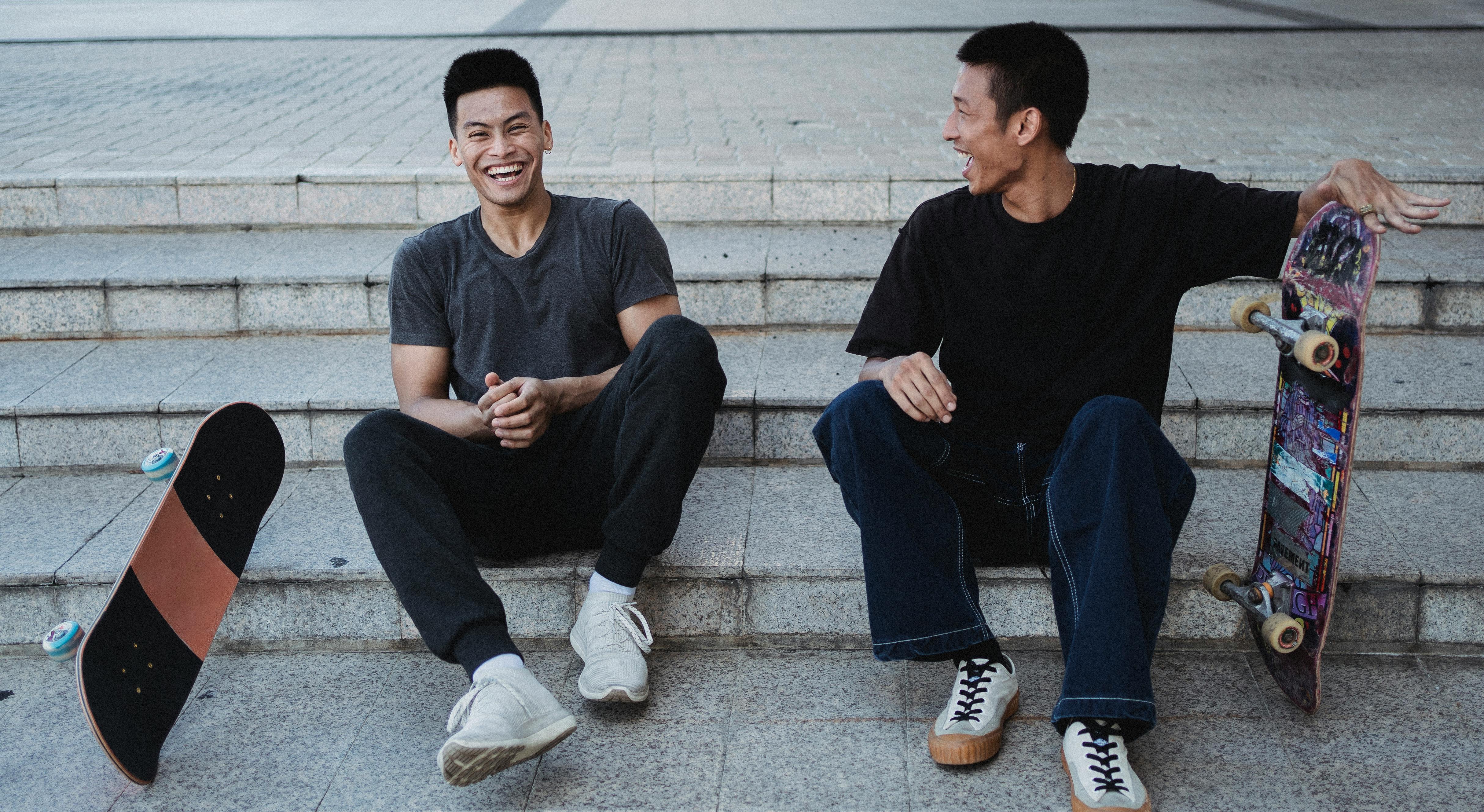 excited happy asian skaters resting on stone stairs