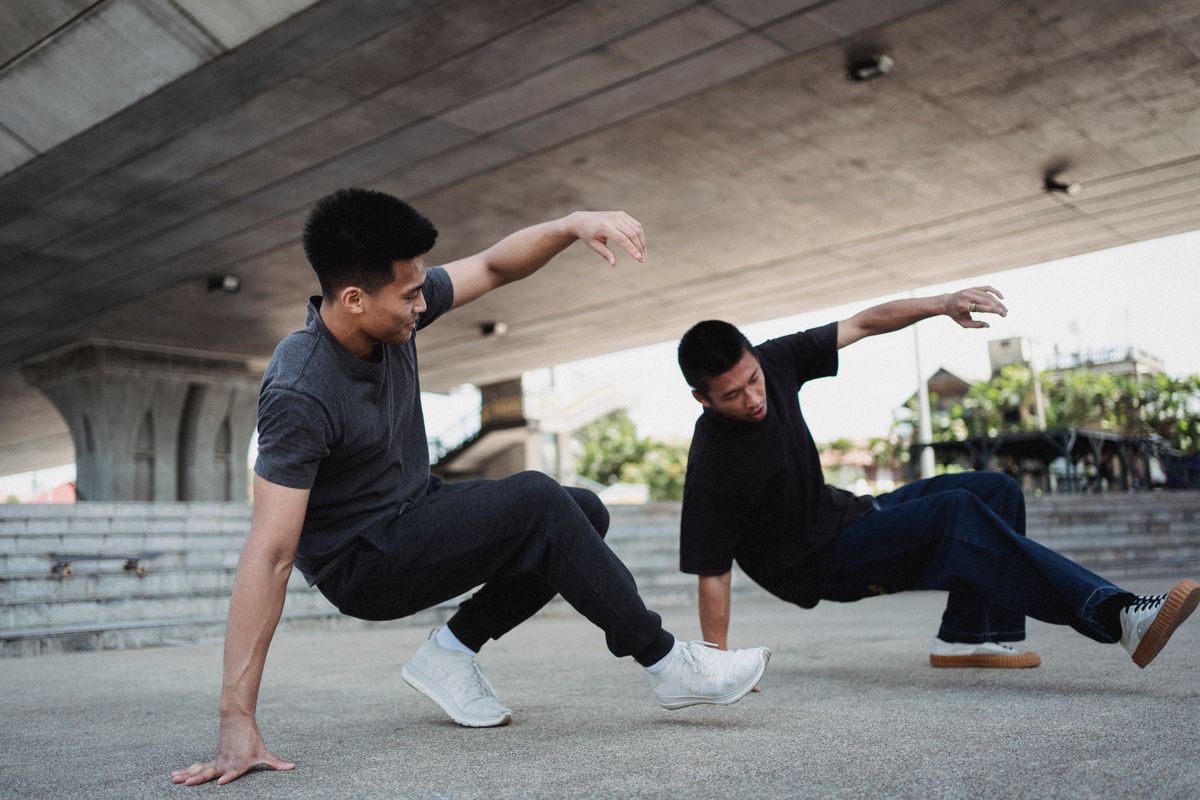 Two dancers breaking under a concrete bridge