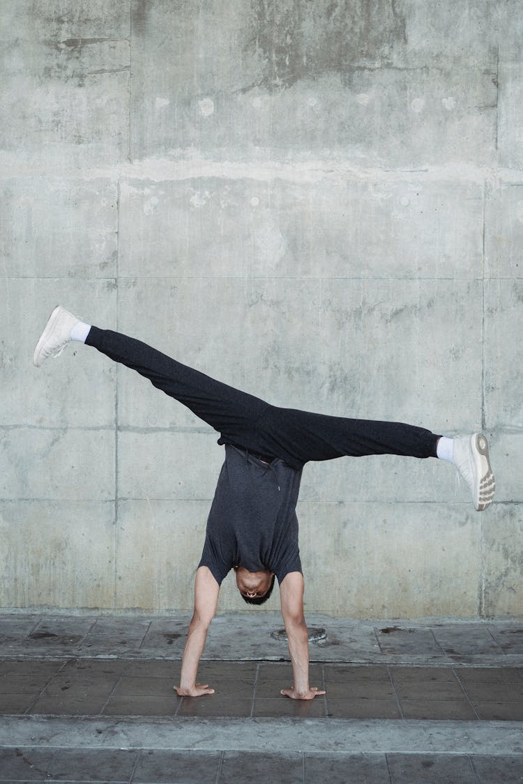 Faceless Man Performing Handstand And Split In Air