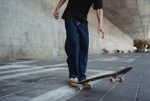 Crop man with skateboard on street