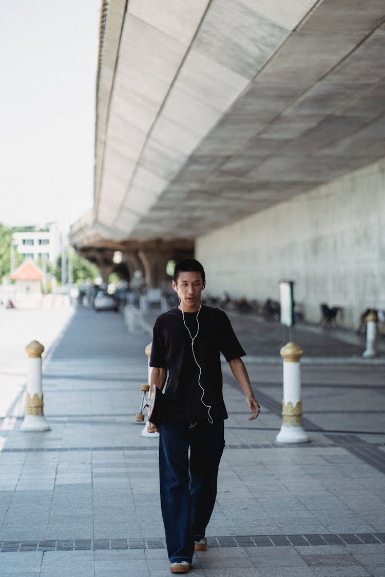 Stylish Asian Man With Skateboard On Street