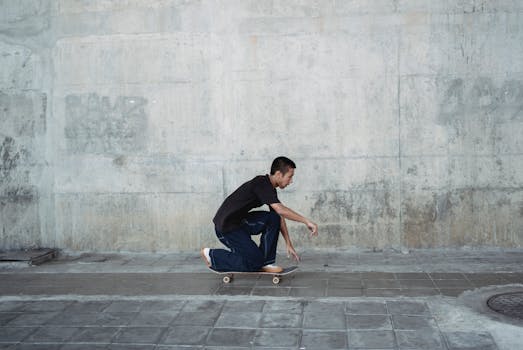 Side view of confident male in casual outfit performing trick on skateboard in sidewalk of street