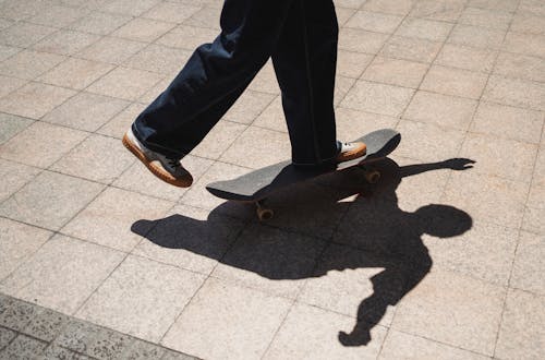 Crop skater riding skateboard on sidewalk