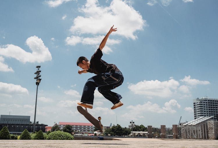 Asian Man Performing Kickflip On Skateboard