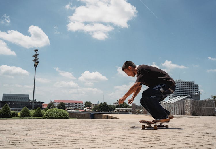 Young Asian Man Riding Skateboard In City