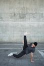 一位自信的年轻霹雳舞者在城市人行道上展示着充满活力的动作