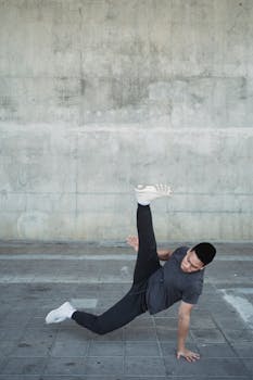 一位自信的年轻霹雳舞者在城市人行道上展示着充满活力的动作