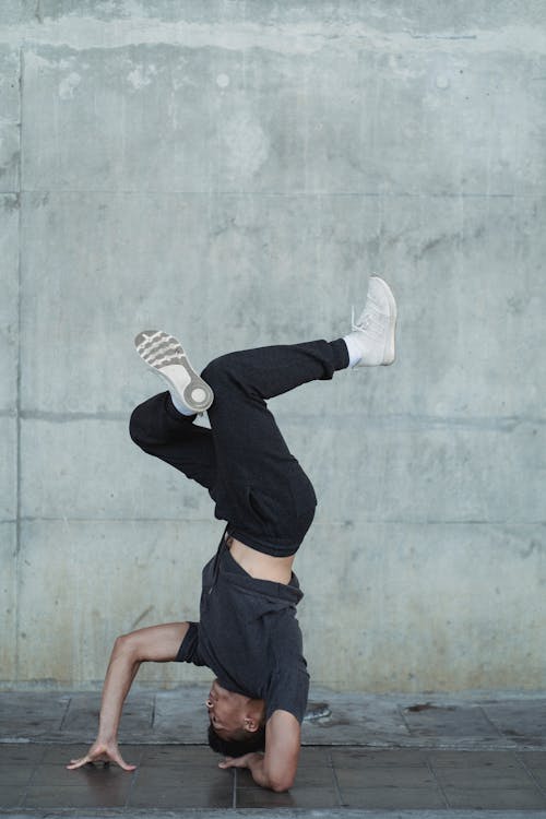 Young guy standing on head during break dance training