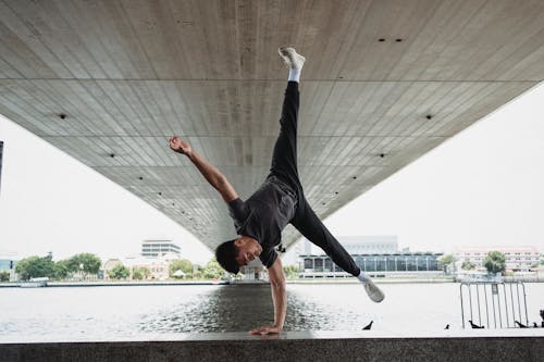 Giovane Che Fa Handstand Sulla Recinzione Dell'argine Del Fiume