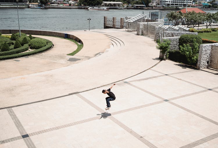 Man Doing Trick With Skateboard On Square