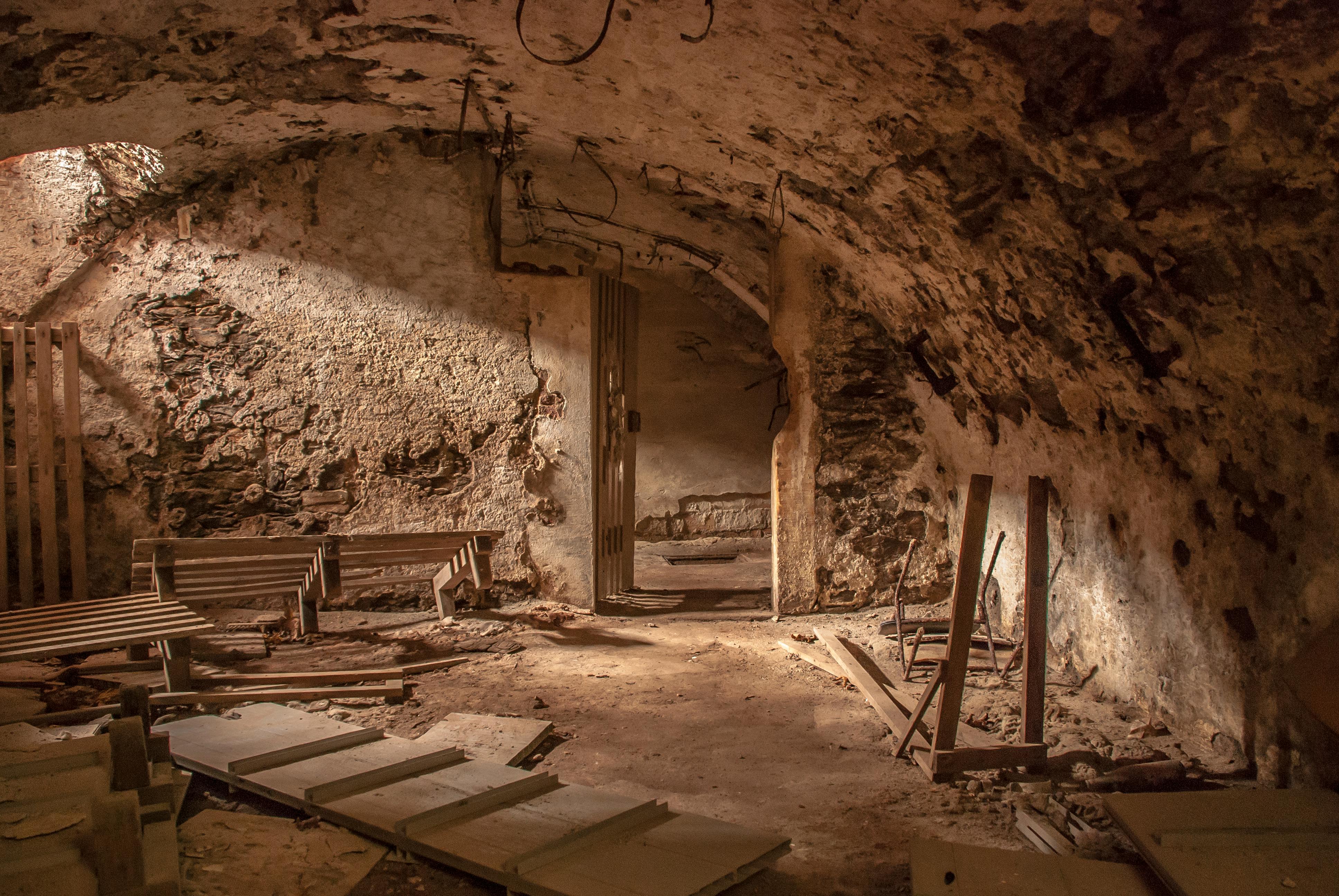 An atmospheric shot of an old, abandoned basement with weathered stone walls and scattered debris.