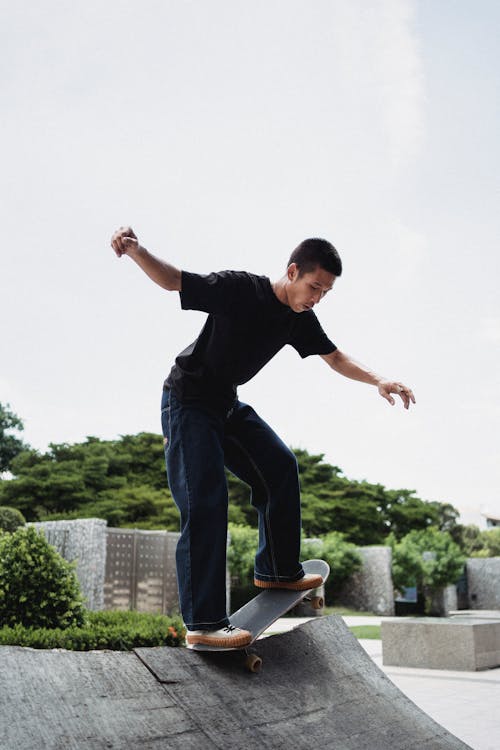 Asian skateboarder balancing on skateboard on city ramp