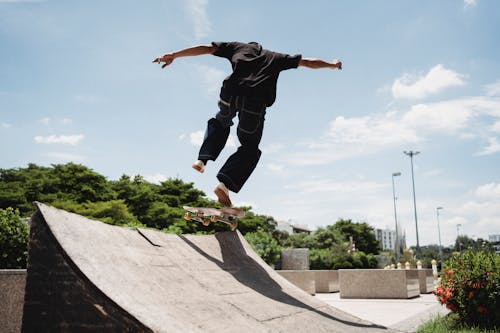 Неузнаваемый скейтбордист выполняет трюк в воздухе над рампой