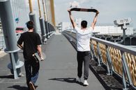城市围栏桥上，一位匿名男性朋友拿着滑板漫步的背影