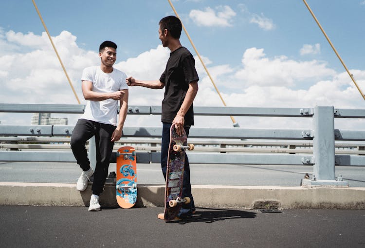 Cheerful Asian Partners Greeting Each Other On Fenced Bridge