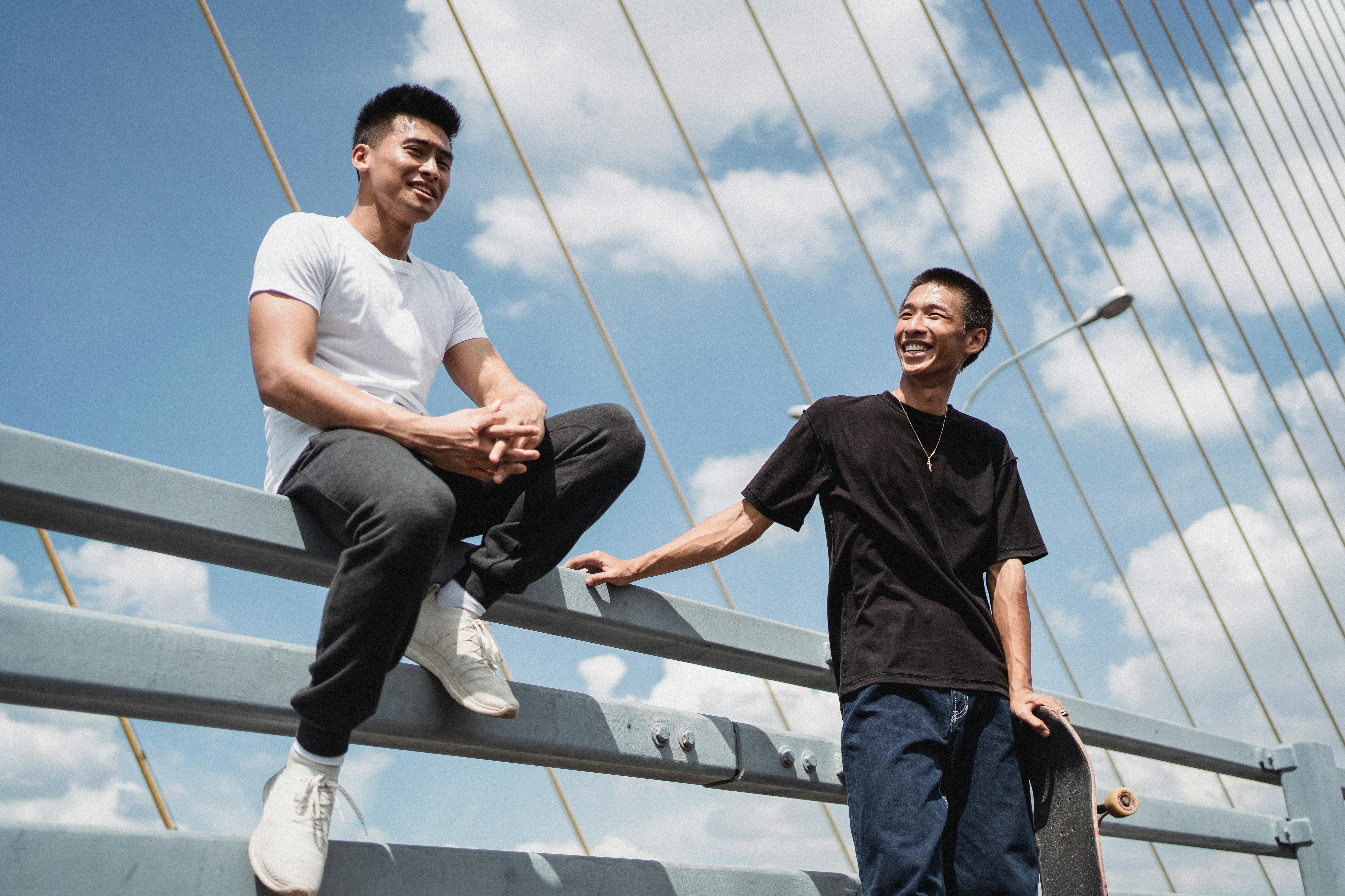 cheerful asian friends interacting on suspension bridge