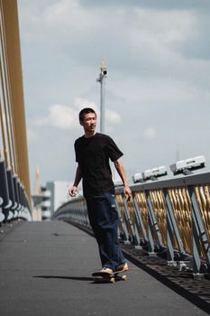一位身材苗条、怀揣梦想的民族运动员，闭着眼睛在城市围栏桥的人行道上滑滑板