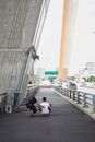 阳光明媚的日子里，两名滑板爱好者在一座现代城市桥下玩耍