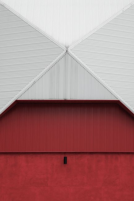 Close-up of a red and white geometric building facade with corrugated metal texture.