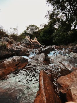 一名女子穿着泳衣，懒洋洋地躺在溪流边的岩石上